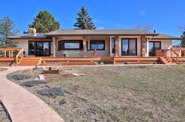 rear view of house with a yard, solar panels, and a deck