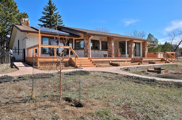 view of front of home featuring roof mounted solar panels, a chimney, and a deck