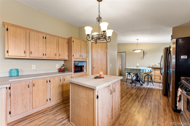 kitchen with light hardwood / wood-style flooring, light brown cabinets, stainless steel range with gas cooktop, a kitchen island, and pendant lighting