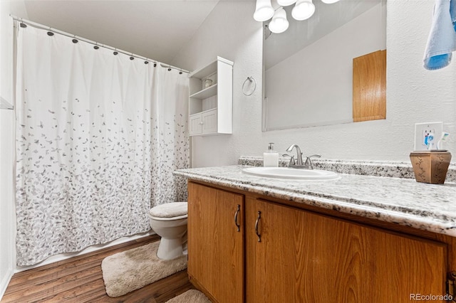 bathroom featuring vanity, hardwood / wood-style floors, lofted ceiling, and toilet