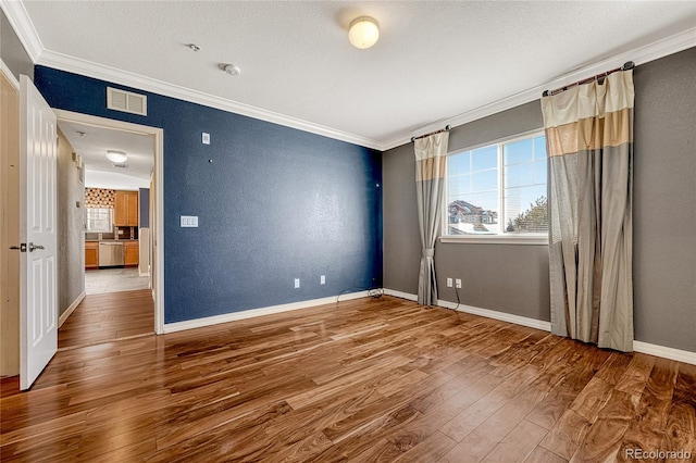 spare room with hardwood / wood-style floors and crown molding