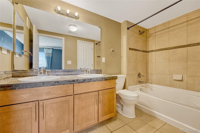 full bathroom with tile patterned flooring, vanity, tiled shower / bath combo, and toilet