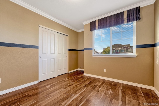 unfurnished bedroom featuring a closet, ornamental molding, and hardwood / wood-style flooring