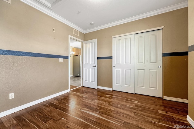 unfurnished bedroom with stainless steel refrigerator, crown molding, a closet, and dark hardwood / wood-style floors