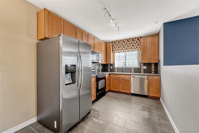 kitchen with decorative backsplash, sink, stainless steel appliances, and track lighting