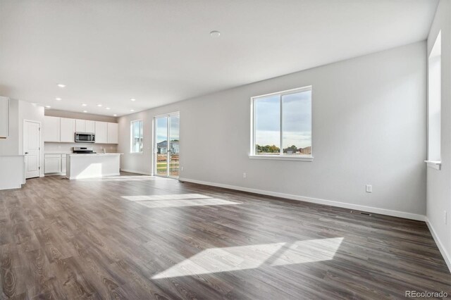 unfurnished living room with wood-type flooring and a wealth of natural light