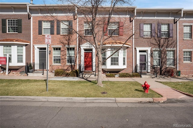 multi unit property featuring a front yard and brick siding