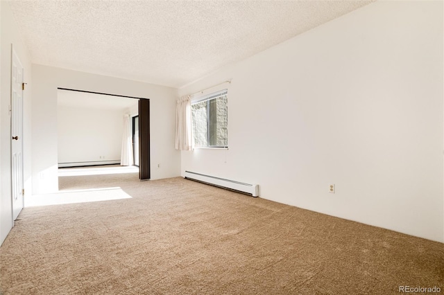 spare room featuring baseboard heating, light carpet, and a textured ceiling