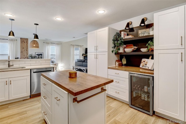 kitchen with stainless steel dishwasher, a center island, hanging light fixtures, beverage cooler, and sink