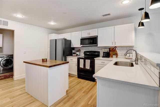 kitchen featuring appliances with stainless steel finishes, pendant lighting, washer / dryer, a kitchen island, and white cabinetry