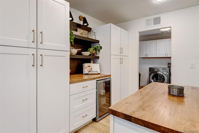 kitchen with washer / dryer, butcher block counters, wine cooler, and white cabinets