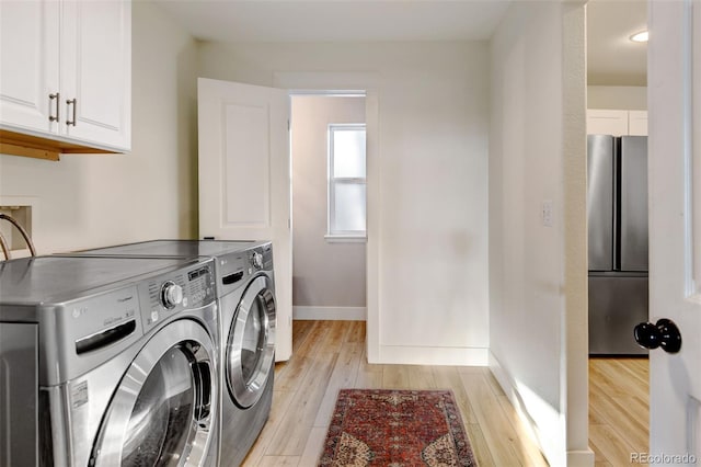 laundry room with light hardwood / wood-style floors, cabinets, and washer and clothes dryer