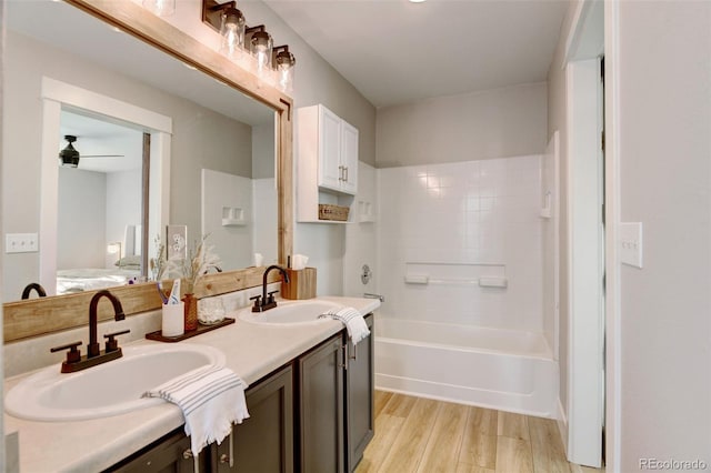 bathroom featuring wood-type flooring, vanity, ceiling fan, and washtub / shower combination