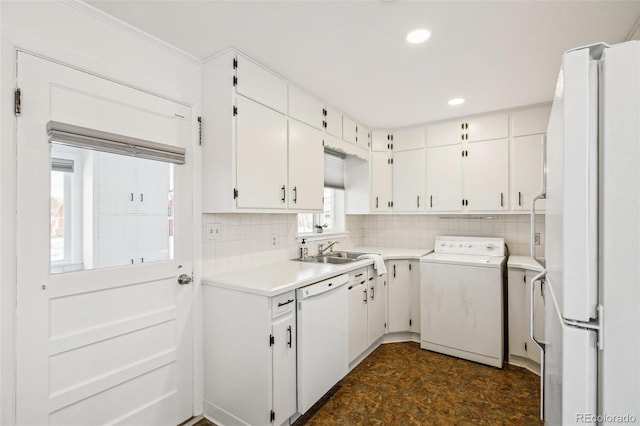 kitchen with sink, white appliances, white cabinetry, backsplash, and washer / dryer