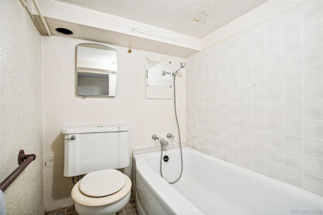 bathroom with a textured ceiling, a tub, and toilet