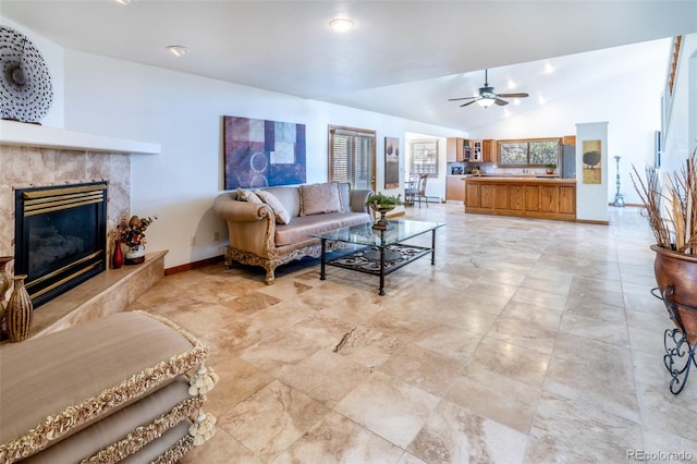 living area with a high end fireplace, baseboards, vaulted ceiling, and a ceiling fan