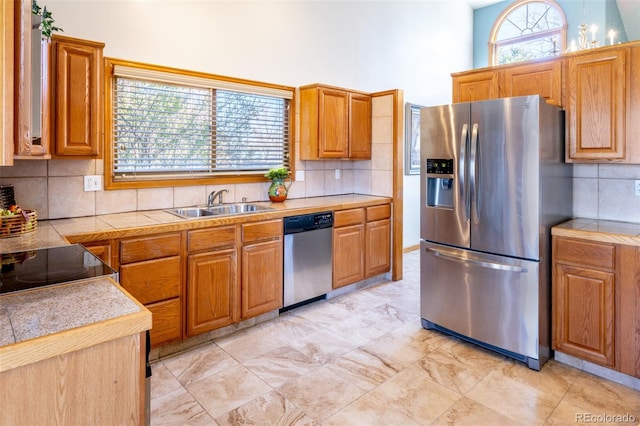 kitchen featuring a sink, light countertops, appliances with stainless steel finishes, brown cabinets, and backsplash