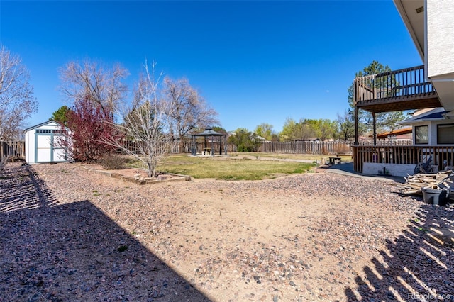 view of yard with a balcony, a gazebo, a fenced backyard, and an outbuilding