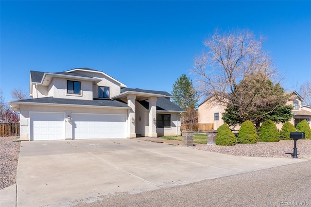 view of front of property with driveway, fence, a garage, and stucco siding