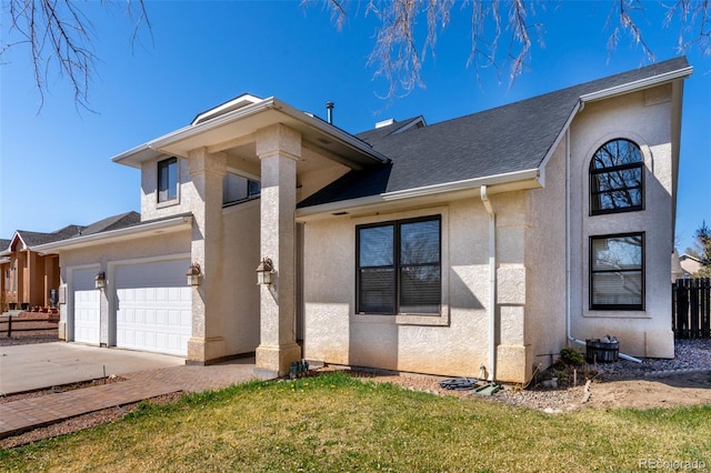 view of front facade with concrete driveway, stucco siding, fence, and a front lawn