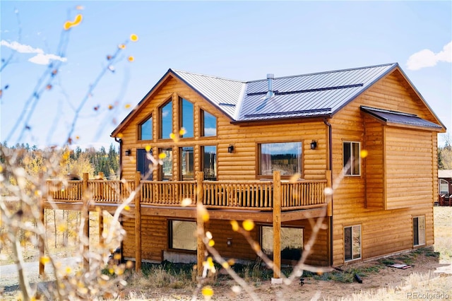 rear view of house featuring metal roof, faux log siding, and a deck