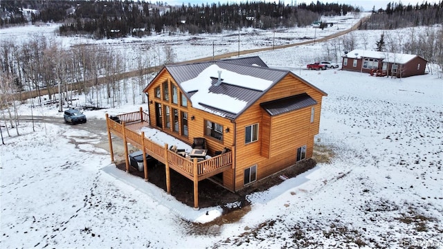 snow covered back of property with a deck