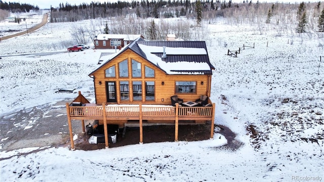 snow covered house featuring a deck and metal roof