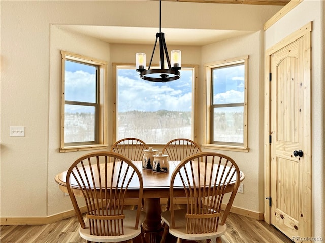 dining space featuring light wood-style flooring, baseboards, and a notable chandelier