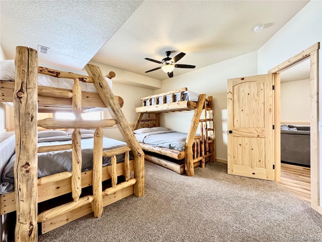 bedroom with ceiling fan, visible vents, a textured ceiling, and carpet flooring