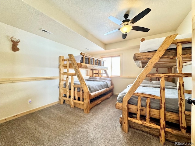 bedroom with a textured ceiling, carpet floors, a ceiling fan, visible vents, and baseboards