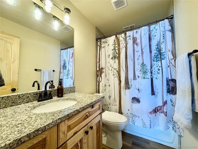 full bathroom with toilet, wood finished floors, vanity, and visible vents