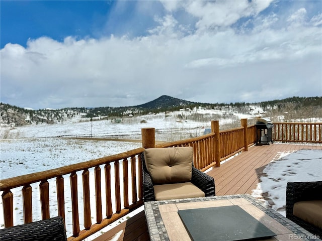 snow covered deck with grilling area and a mountain view