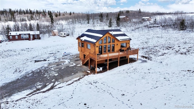 snow covered property with a deck and an outdoor structure