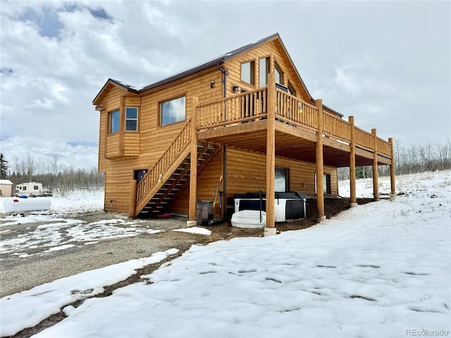 snow covered back of property with stairs and a deck