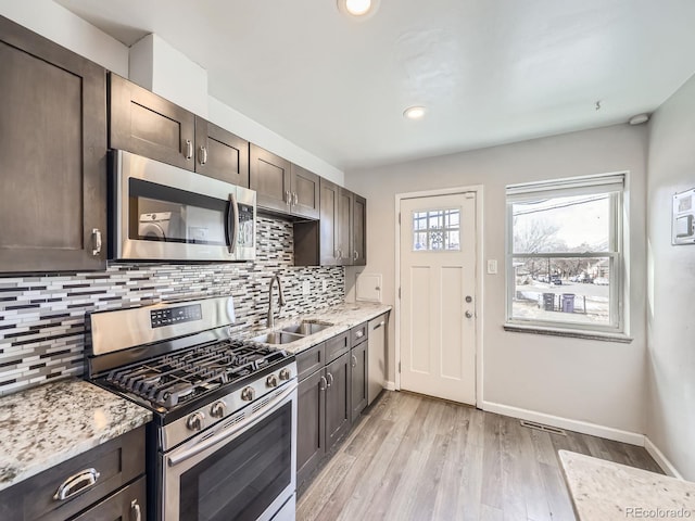 kitchen with appliances with stainless steel finishes, light stone counters, and dark brown cabinetry