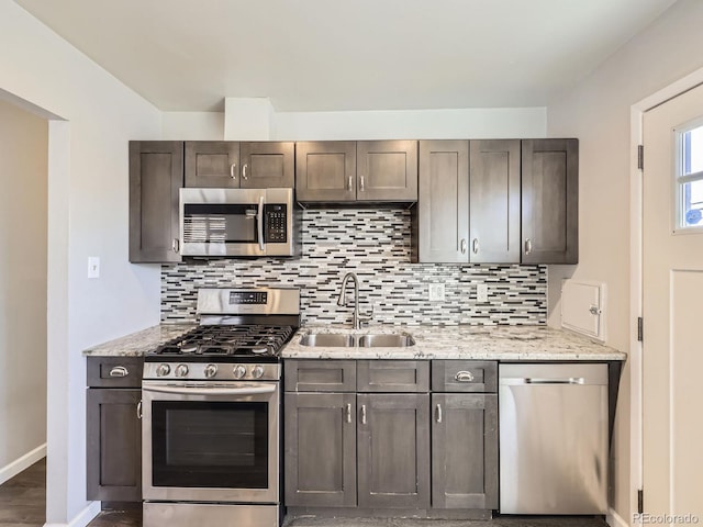 kitchen featuring appliances with stainless steel finishes, sink, backsplash, light stone countertops, and dark brown cabinets