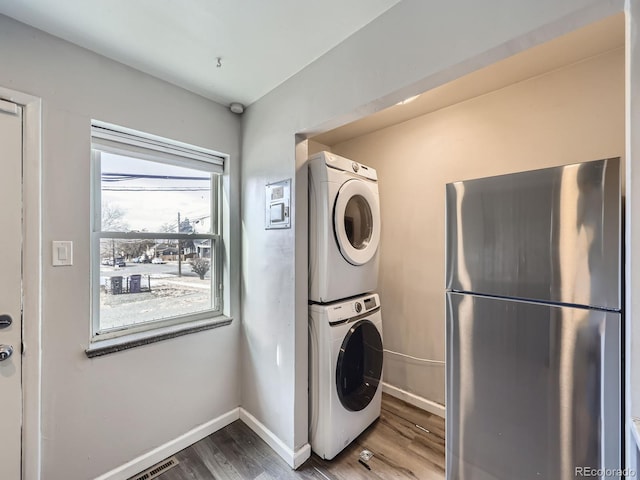 clothes washing area with hardwood / wood-style flooring and stacked washing maching and dryer