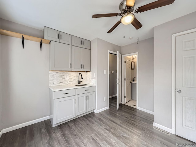 kitchen with sink, decorative backsplash, wood-type flooring, and ceiling fan