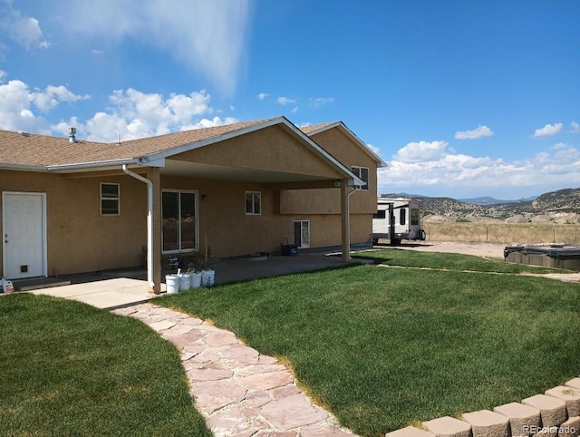 back of house featuring a mountain view, a lawn, and a patio