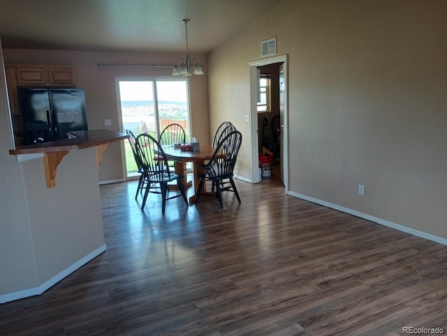 dining space with dark hardwood / wood-style flooring, a notable chandelier, and lofted ceiling