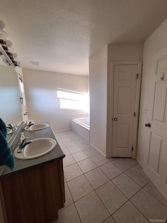 bathroom featuring vanity, tiled tub, tile patterned flooring, and a textured ceiling