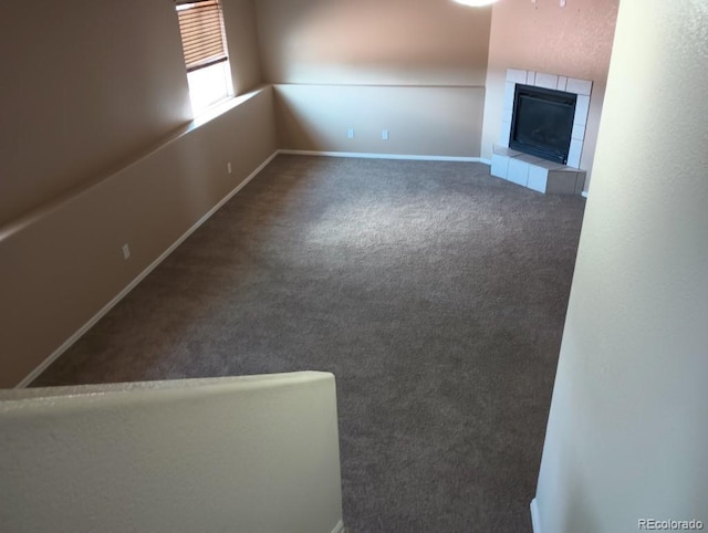 unfurnished living room with a tiled fireplace and carpet floors