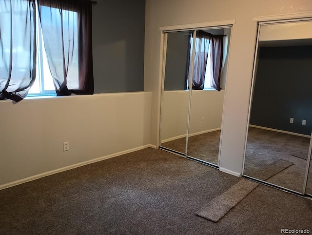 unfurnished bedroom with multiple windows, two closets, and carpet