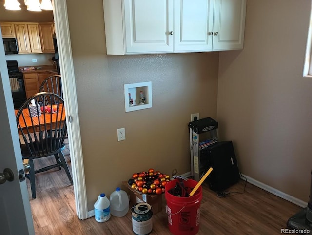 clothes washing area featuring electric dryer hookup, hookup for a washing machine, wood-type flooring, and cabinets