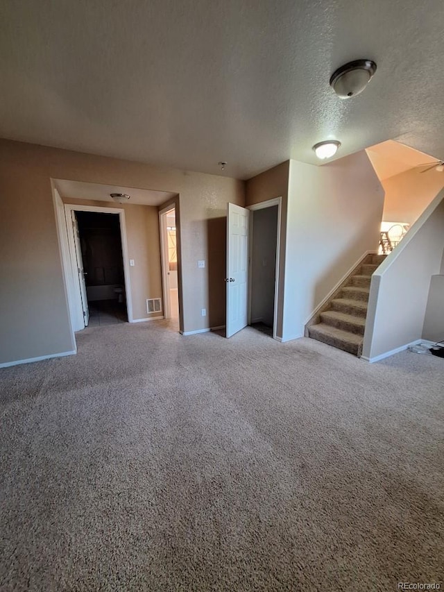 unfurnished living room featuring a textured ceiling and carpet flooring