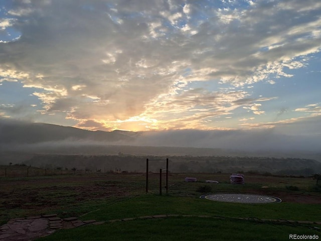 yard at dusk featuring a rural view and a mountain view