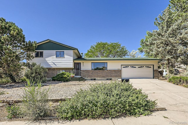 tri-level home with an attached garage, brick siding, and driveway