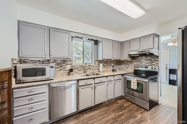 kitchen with under cabinet range hood, gray cabinets, appliances with stainless steel finishes, and a sink