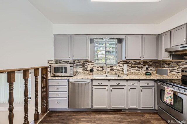 kitchen featuring under cabinet range hood, stainless steel appliances, gray cabinets, and a sink