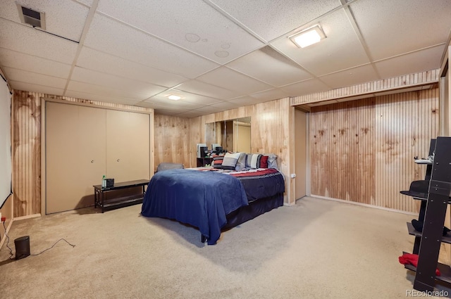 bedroom with a drop ceiling, carpet, visible vents, and wood walls